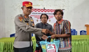 Kepala SPN Polda Sulteng, AKBP Seminar Sebayang menyerahkan bantuan kepada warga dalam kegiatan sosial di labuan Panimba, DOnggala , Selasa (3/6/2025). (Fot: Humas Polda Sulteng)